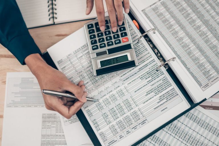 Investors working on desk office and using a calculator to calculate balance, profit, currency and cost. Accounting and  Financial concept.